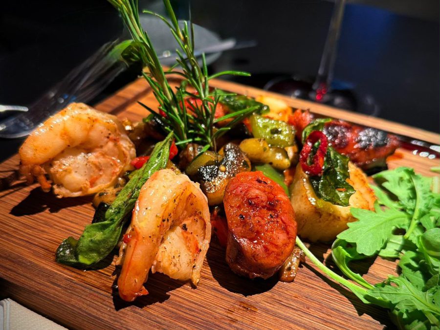 Garnelen mit Chorizo, Gemüse und Rosmarin auf einem Holzbrett serviert